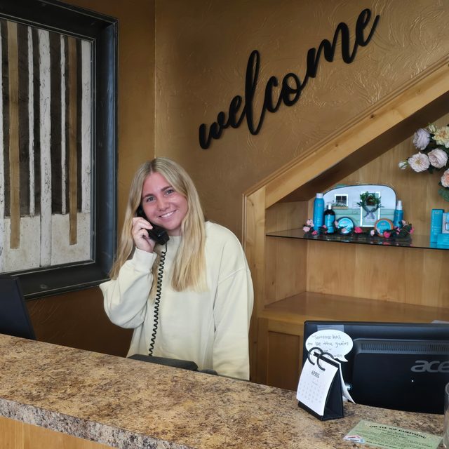 The reception desk at Off The Top Hairstyling, with the welcome sign and retail shelves behind it