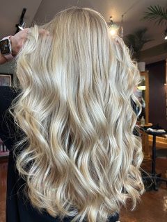 Long blonde waves with soft highlights, being sectioned by a stylist